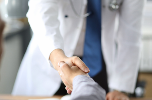 CRO professional in white lab coat shaking hands to represent clinical research for immune checkpoint inhibitors